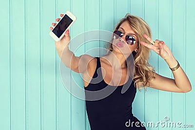 Blonde woman in bodysuit with perfect body taking selfie smartphone toned instagram filter Stock Photo