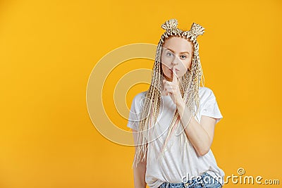 Blonde woman gesturing hush to be quiet. Secret concept. Beautiful caucasian woman with kanekalons isolated on yellow background Stock Photo