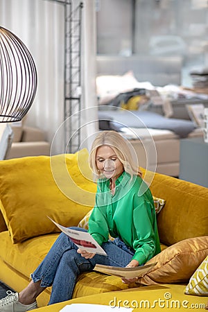 Blonde woman in a green blouse looking holding a picture in her hand Stock Photo