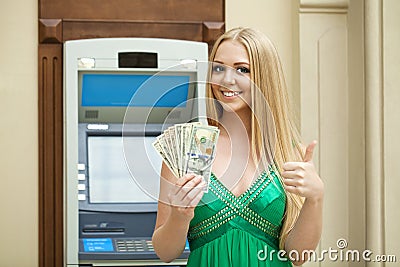 Blonde woman in a green dress is holding a cash dollars Stock Photo