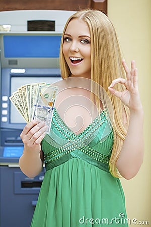 Blonde woman in a green dress is holding a cash dollars Stock Photo