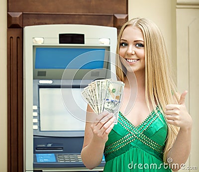 Blonde woman in a green dress is holding a cash dollars Stock Photo