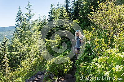 Blonde woman hiker hikes downhill on an Oregon trail in Mt Hood Stock Photo