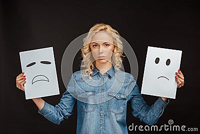Blonde woman holding cards with sad emotions on black Stock Photo