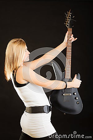 Blonde woman holding electric guitar, black background Stock Photo