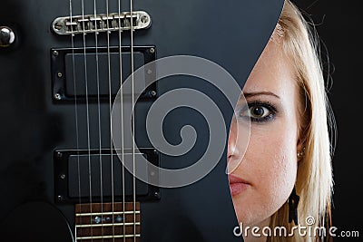 Blonde woman holding electric guitar, black background Stock Photo