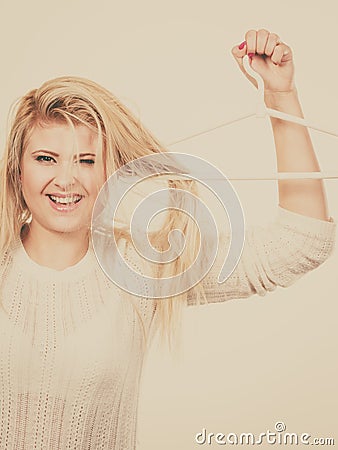 Blonde woman holding hair on clothes hanger Stock Photo