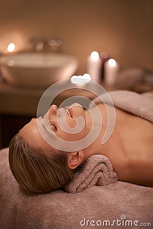 Blonde woman, massage therapy and candlelight for wellness, smile and relaxation to destress and pamper. Female person Stock Photo