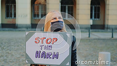 Blonde woman in protective mask protesting to stop harm by holding steamer Stock Photo