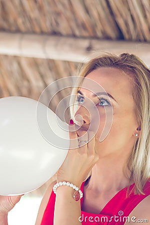 Blonde woman blowing white balloon Stock Photo