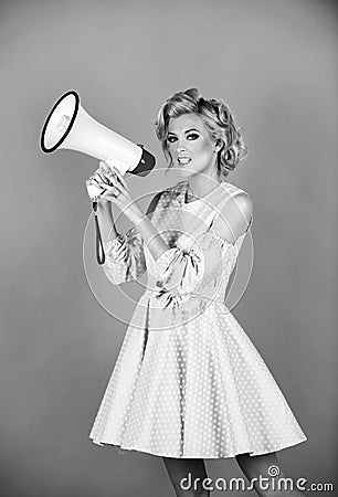 Blonde woman in retro style shouting through a megaphone. Shout girl speaks in a loudspeaker megaphone. Stock Photo