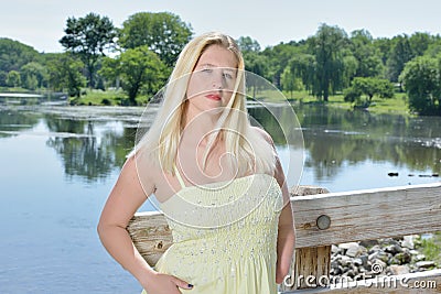 Blonde woman in yellow sundress poses on bridge Stock Photo