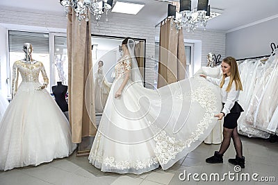 Blonde woman helping bride in wedding shop Stock Photo