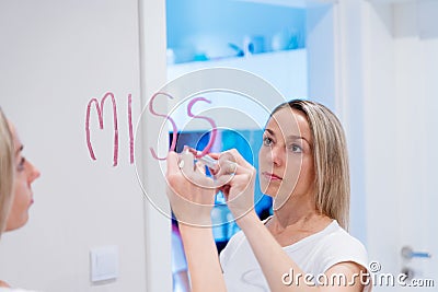 The blonde writes the words I miss you on the mirror with a lipstick. Stock Photo