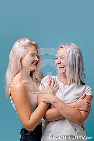 Blondehaired Mom and teenager daughter smiling on colorful backgroung. studio shoot with copy space Stock Photo