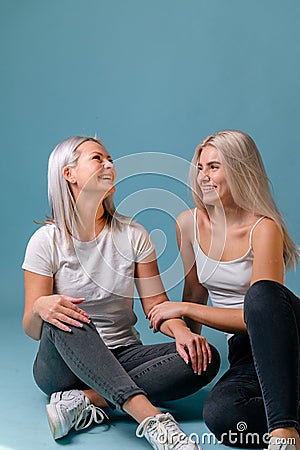 Blondehaired Mom and teenager daughter smiling on colorful backgroung. studio shoot with copy space Stock Photo