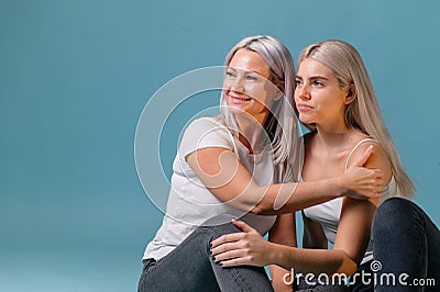 Blondehaired Mom and teenager daughter smiling on colorful backgroung. studio shoot with copy space Stock Photo