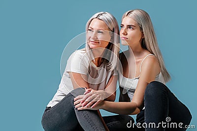 Blondehaired Mom and teenager daughter smiling on colorful backgroung. studio shoot with copy space Stock Photo