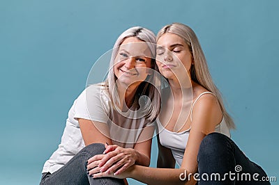 Blondehaired Mom and teenager daughter smiling on colorful backgroung. studio shoot with copy space Stock Photo