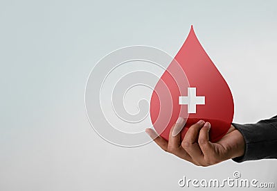 Blood Donation Concept. Help, Care, Love, Support. Hand Holding a Red Drop and Cross Stock Photo