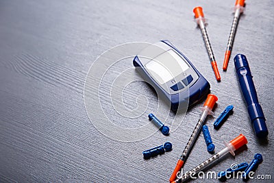 Blood glucose meter, needles and several insulin syringes on a gray wooden table, flat lay with copy space Stock Photo