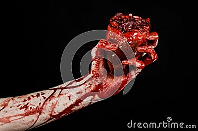 Blood and Halloween theme: terrible bloody hand hold torn bleeding human heart isolated on black background in studio Stock Photo