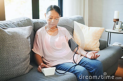 Blood pressure, healthcare and senior woman in living room with equipment for hypertension. Sick, illness and elderly Stock Photo