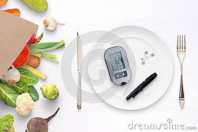 Blood sugar meter with strips in a plate concept. Bag with healthy food and vegetables beside Stock Photo