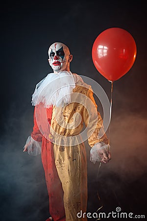 Bloody clown in carnival costume holds air balloon Stock Photo