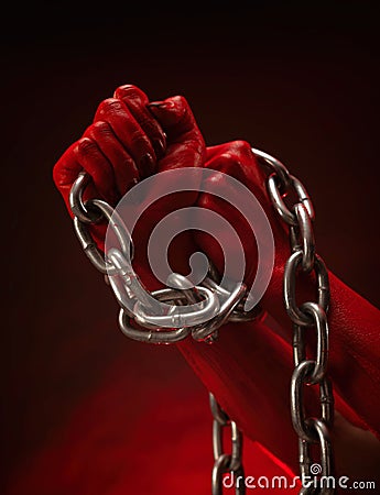 bloody hands clenched into fists in the shackles of a metal chain symbol of slavery, protest and freedom Stock Photo