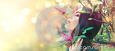 Blooming magnolia trees. Beauty young woman touching and smelling spring magnolia flowers Stock Photo