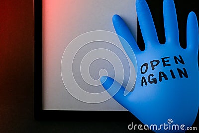 Blown up blue latex surgical glove on black background. Reopening covid safe. Open again text written on medical glove Stock Photo