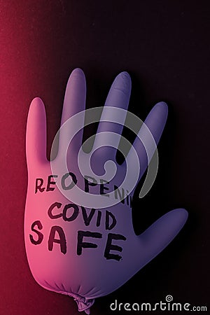 Blown up blue latex surgical glove on black background. Reopening covid safe. Open again text written on medical glove Stock Photo