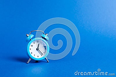 A blue alarm clock on a blue background. Limited offer and over time. Planning and discipline. waiting for a meeting. Punctuality Stock Photo