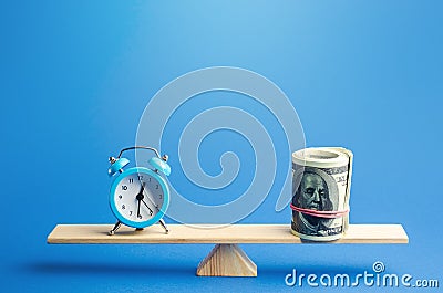 Blue alarm clock and a bundle of dollars on scales. Fair hourly wages. Time tracking. Deposit, money investment. Profitability Stock Photo