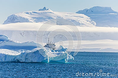 Blue antarctic cruise vessel among the icebergs with glacier in Stock Photo