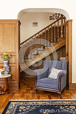 Blue armchair against wooden stairs in classic living room inter Stock Photo
