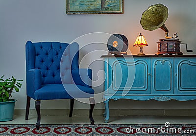 Blue armchair, vintage wooden light blue sideboard, lighted antique table lamp, old phonograph gramophone and vinyl records Stock Photo