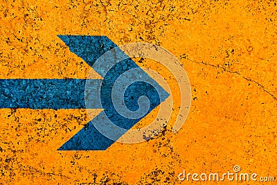 Blue arrow direction sign over vivid bright orange color stone wall with imperfections and cracks Stock Photo