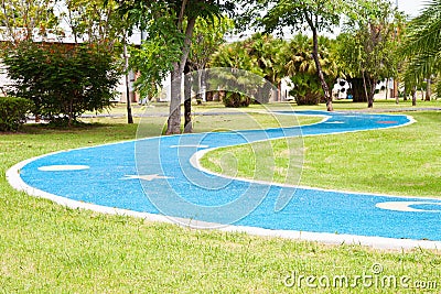 Blue asphalt path via green grass Stock Photo