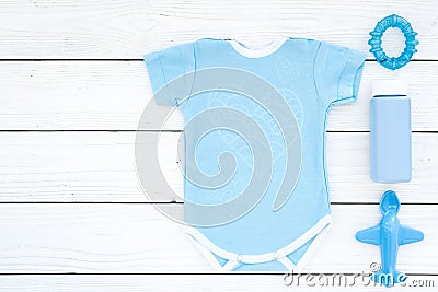 Blue baby clothes for little boy. Bodysuit, toys, cosmetics on white wooden background top view copy space Stock Photo