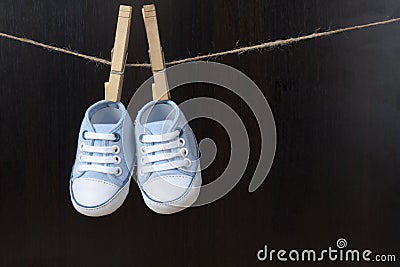 Blue baby sneakers hung with clamps on a string Stock Photo