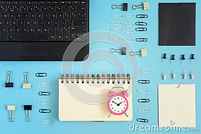 On a blue background neatly spread out clerical clips and clothespins. In the corner is a black laptop. On the open page Stock Photo