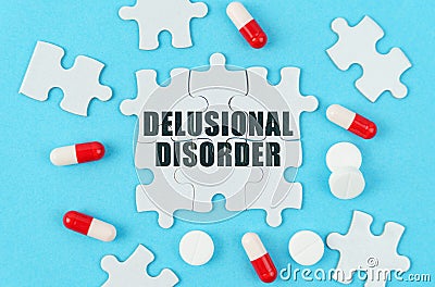 On a blue background, pills, capsules and puzzles with the inscription - Delusional disorder Stock Photo