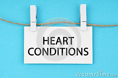 On a blue background, a white plaque hangs on a rope with the inscription - HEART CONDITIONS Stock Photo