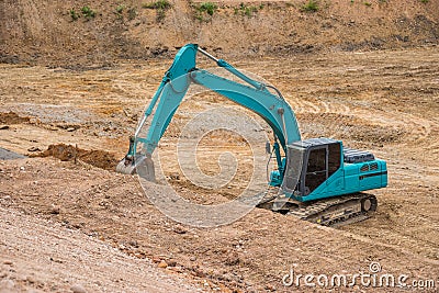 Blue backhoe excavating soil and sand Stock Photo