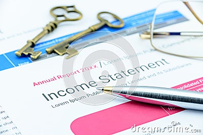 Blue ballpoint pen on a corp's income statement with two antique brass keys and eye glasses. Stock Photo