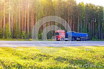 Blue barrel truck with dangerous cargo is parked on the side of a forest road Stock Photo