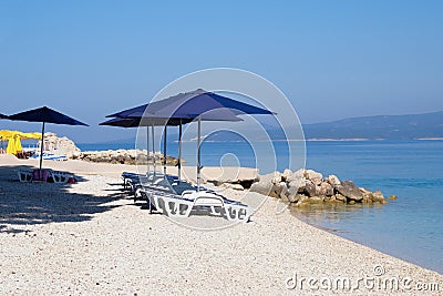 Blue beach umbrellas and chaise for relax and comfort on sea resort. Summer vacations and travel for seaside. Paid service on Stock Photo