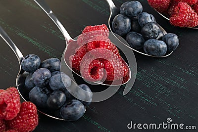 blue-berries and raspberries in iron spoons on a dark background Stock Photo